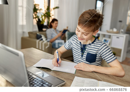 student boy with book writing to notebook at home student boy with book writing to notebook at home 66868876