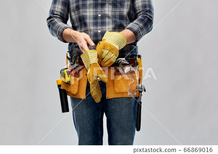 builder with working tools putting gloves on builder with working tools putting gloves on 66869016