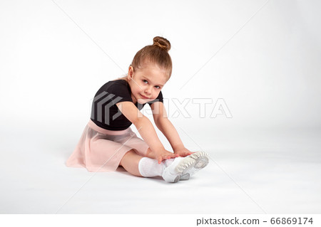 Little girl doing stretching and gymnastic exercises on a white background. 66869174