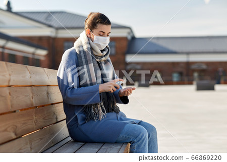 woman in mask spraying hand sanitizer outdoors 66869220