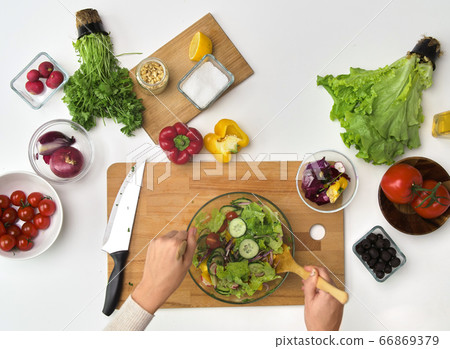 hands cooking vegetable salad on kitchen table hands cooking vegetable salad on kitchen table 66869379