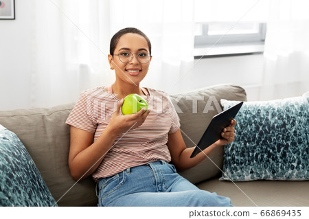 african woman with tablet pc and apple at home african woman with tablet pc and apple at home 66869435