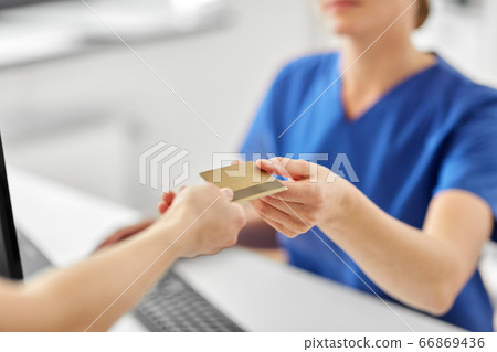 patient giving doctor credit card at hospital 66869436