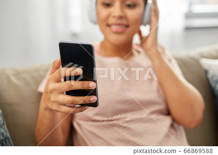 woman with smartphone listening to music at home woman with smartphone listening to music at home 66869588