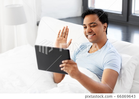happy man with tablet pc in bed having video call happy man with tablet pc in bed having video call 66869643