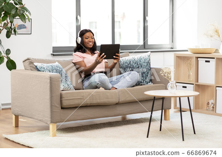 woman with tablet pc listening to music at home 66869674