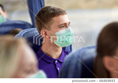 young man in medical mask sitting in travel bus 66869693