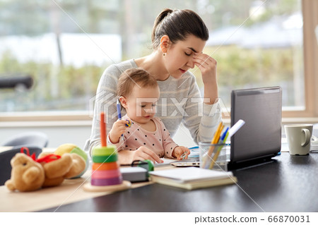 tired mother with baby working at home office 66870031