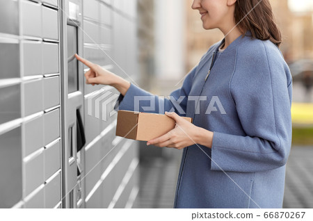 smiling woman with box at automated parcel machine smiling woman with box at automated parcel machine 66870267