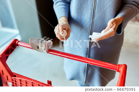 woman cleaning shopping cart handle with sanitizer 66870391