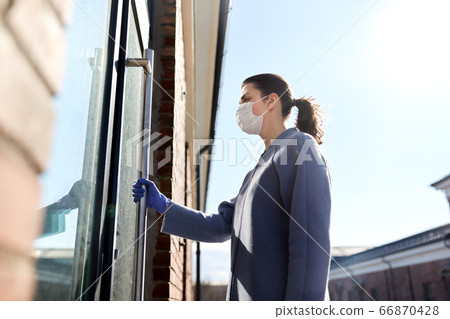 woman in mask and glove holding to door handle woman in mask and glove holding to door handle 66870428