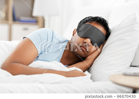 indian man in eye mask sleeping in bed at home indian man in eye mask sleeping in bed at home 66870430