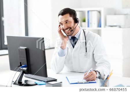 happy doctor with computer and headset at hospital 66870455
