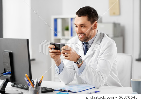 smiling male doctor with smartphone at hospital smiling male doctor with smartphone at hospital 66870543
