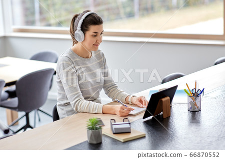 woman in headphones with tablet pc working at home woman in headphones with tablet pc working at home 66870552