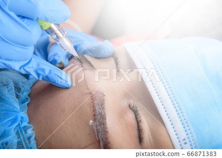Permanent makeup for Eyebrows having professional eyebrow tattoo in beauty salon. 66871383