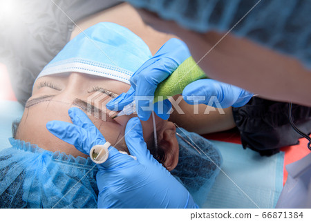 Permanent makeup for Eyebrows having professional eyebrow tattoo in beauty salon. 66871384