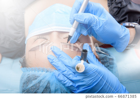 Permanent makeup for Eyebrows having professional eyebrow tattoo in beauty salon. 66871385