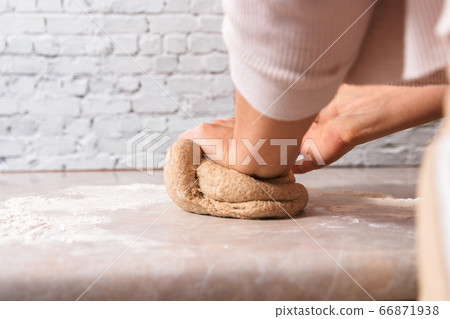 process of baking health bread at home. low angle closeup woman hands kneading dough from rye flour on marble countertop in bright kitchen process of baking health bread at home. low angle closeup woman hands kneading dough from rye flour on marble countertop in bright kitchen 66871938