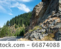 Serpentine road in the mountains. Summer sunny landscape with tall pines and rocks 66874088