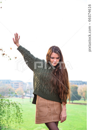 Girl puts aside tree branch and looks sideways Girl puts aside tree branch and looks sideways 66874616