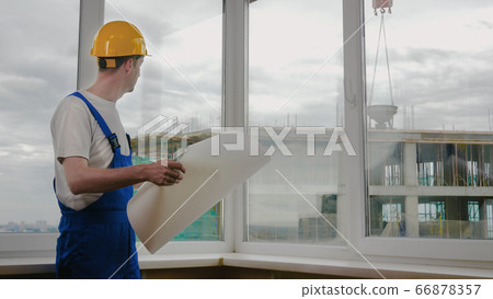Builder at construction site with blueprint. Builder at construction site with blueprint. 66878357