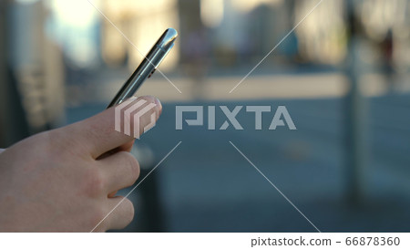 Hipster man hands using his smartphone outdoor in the park. Hipster man hands using his smartphone outdoor in the park. 66878360