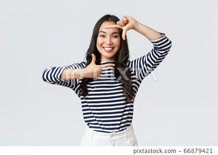 Lifestyle, people emotions and casual concept. Creative cute asian girl picturing, capture moment with hand frames gesture, smiling amused, staying positive and happy, white background 66879421
