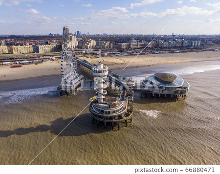 Pier with Ferris Wheel at Northern Sea Scheveningen Beach , located near the Hague city aerial drone footage. Popular Dutch beach resort Scheveningen With a clouds on the Sky in a day Pier with Ferris Wheel at Northern Sea Scheveningen Beach , located near the Hague city aerial drone footage. Popular Dutch beach resort Scheveningen With a clouds on the Sky in a day 66880471
