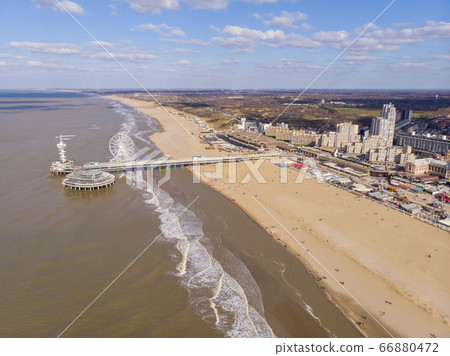 Pier with Ferris Wheel at Northern Sea Scheveningen Beach , located near the Hague city aerial drone footage. Popular Dutch beach resort Scheveningen With a clouds on the Sky in a day Pier with Ferris Wheel at Northern Sea Scheveningen Beach , located near the Hague city aerial drone footage. Popular Dutch beach resort Scheveningen With a clouds on the Sky in a day 66880472