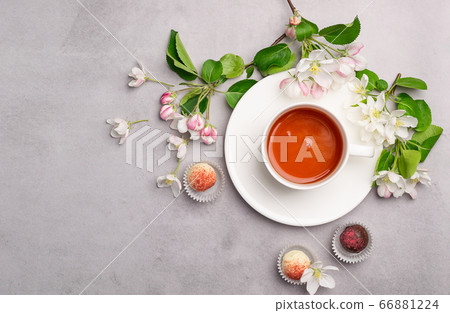 Chocolates of various colors in a festive elegant box packing a cup of tea on pastel pink background decoration flowers. Chocolates of various colors in a festive elegant box packing a cup of tea on pastel pink background decoration flowers. 66881224
