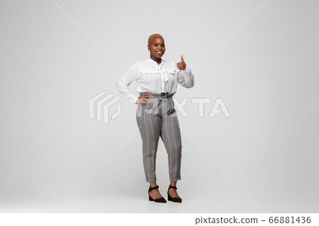 Young african-american woman in office attire on gray background. Bodypositive female character. plus size businesswoman Young african-american woman in office attire on gray background. Bodypositive female character. plus size businesswoman 66881436