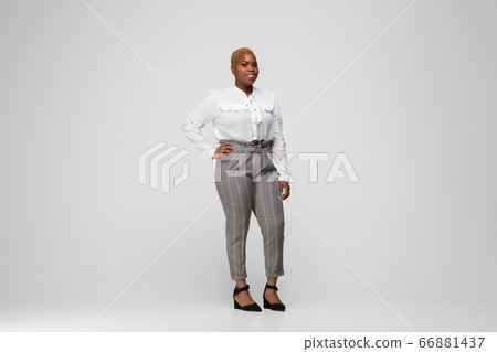 Young african-american woman in office attire on gray background. Bodypositive female character. plus size businesswoman Young african-american woman in office attire on gray background. Bodypositive female character. plus size businesswoman 66881437