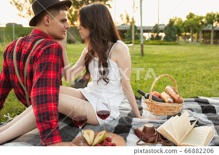 Caucasian young and happy couple enjoying a picnic in the park on summer day Caucasian young and happy couple enjoying a picnic in the park on summer day 66882206