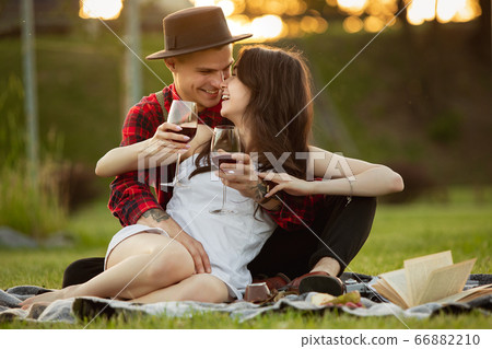 Caucasian young and happy couple enjoying a picnic in the park on summer day Caucasian young and happy couple enjoying a picnic in the park on summer day 66882210
