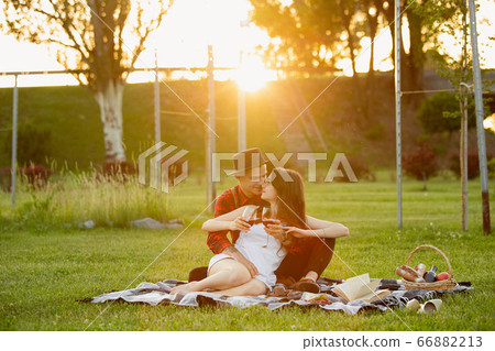 Caucasian young and happy couple enjoying a picnic in the park on summer day Caucasian young and happy couple enjoying a picnic in the park on summer day 66882213