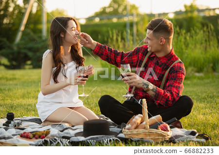 Caucasian young and happy couple enjoying a picnic in the park on summer day Caucasian young and happy couple enjoying a picnic in the park on summer day 66882233
