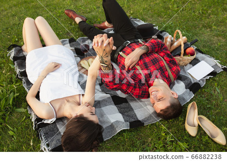 Caucasian young and happy couple enjoying a picnic in the park on summer day Caucasian young and happy couple enjoying a picnic in the park on summer day 66882238