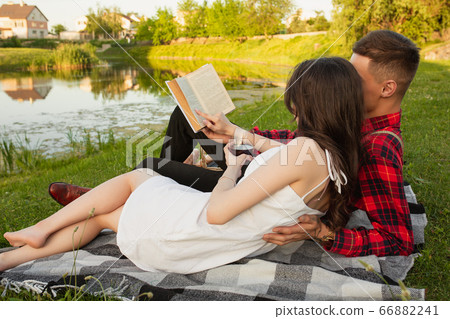Caucasian young and happy couple enjoying a picnic in the park on summer day Caucasian young and happy couple enjoying a picnic in the park on summer day 66882241