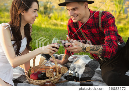 Caucasian young and happy couple enjoying a picnic in the park on summer day Caucasian young and happy couple enjoying a picnic in the park on summer day 66882272
