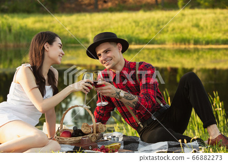 Caucasian young and happy couple enjoying a picnic in the park on summer day Caucasian young and happy couple enjoying a picnic in the park on summer day 66882273
