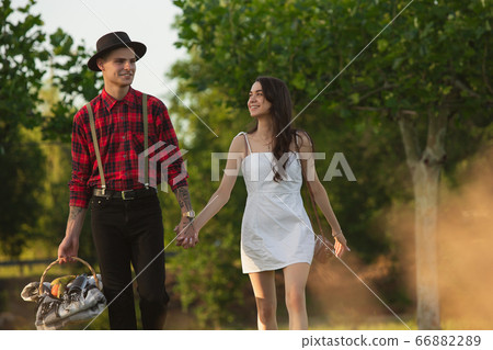 Caucasian young and happy couple enjoying a picnic in the park on summer day Caucasian young and happy couple enjoying a picnic in the park on summer day 66882289