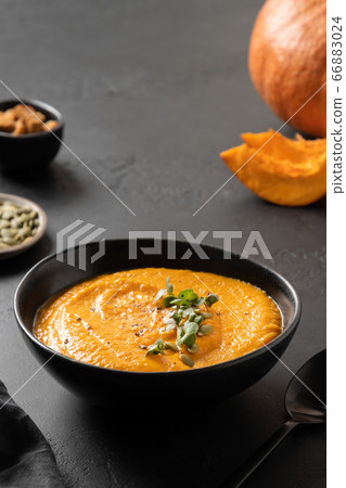 Fall pumpkin soup garnish microgreens on black 66883024