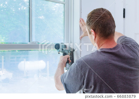 Worker installing trim around a window 66883879