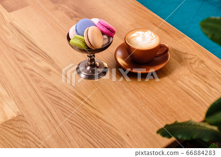 macaroons in a metal bowl and a cup of coffee on a 66884283