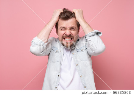 Young man in shock holding hands on head. Young man in shock holding hands on head. 66885868