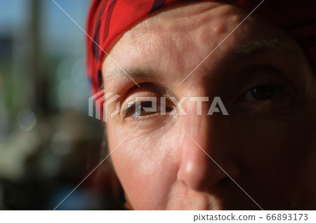 Close-up female portrait of tired mature woman dressed in red clothes and sitting at the end of her work day on sewing machine and cotton bobbins background, tailor profession concept Close-up female portrait of tired mature woman dressed in red clothes and sitting at the end of her work day on sewing machine and cotton bobbins background, tailor profession concept 66893173