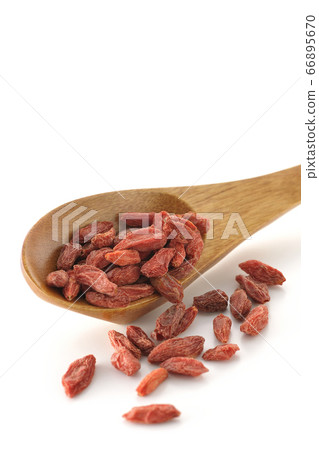 Wolfberry (white background) spilling from a wooden lotus flower 66895670
