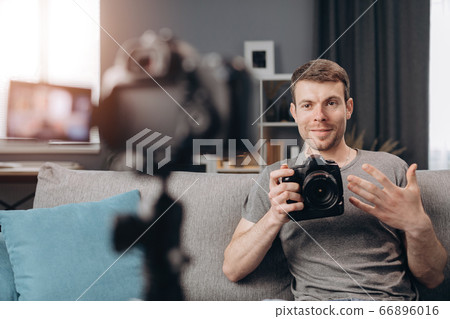 Young bearded man doing video review of new digital camera 66896016