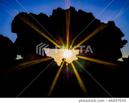 Tourist enjoying taking pictures at sunset at the famous rock formation called La Fenetre, Isalo National Park, Madagascar 66897650